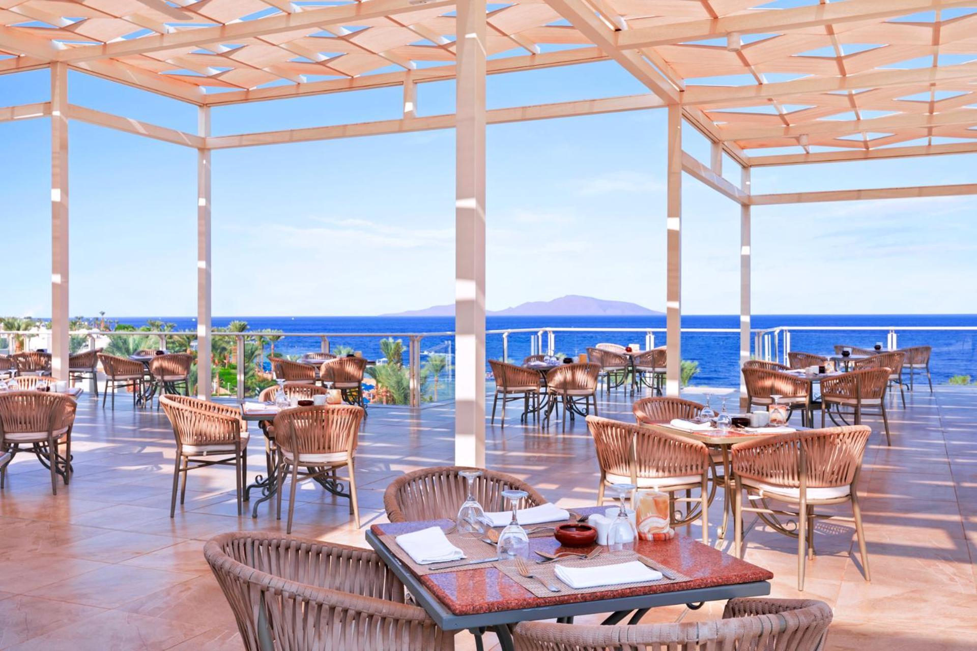 Pickalbatros Royal Grand Sharm - Adults Friendly 16 Years Plus Екстериор снимка The photo shows a spacious outdoor restaurant with a beautiful view of the ocean. The seating area features several tables and wicker chairs. The open design includes a wooden pergola providing some shade, while large windows or openings allow for a 