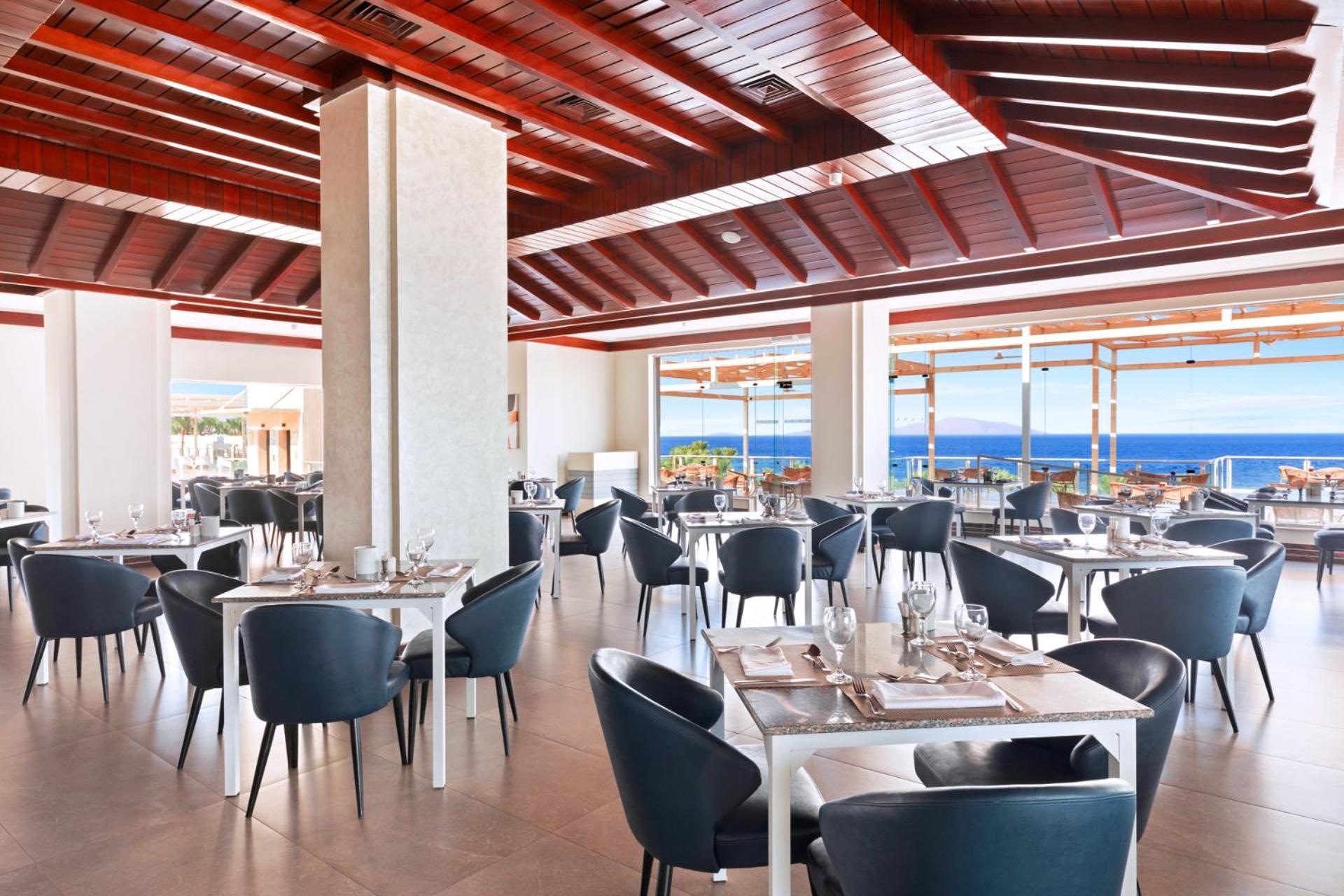 Pickalbatros Royal Grand Sharm - Adults Friendly 16 Years Plus Екстериор снимка The photo shows a modern restaurant interior with a spacious and well-lit design. There are several tables set for dining, featuring white tablecloths and elegant dinnerware. The chairs are sleek and dark, contrasting with the bright surroundings. La
