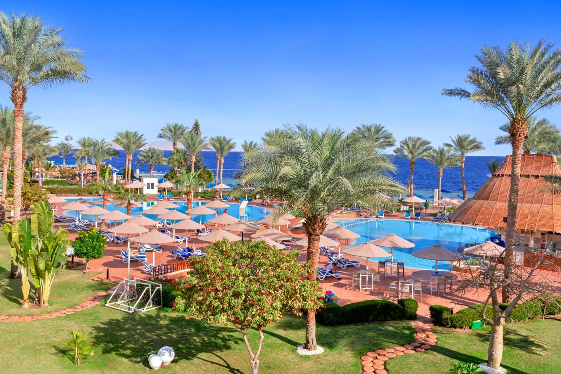 Pickalbatros Royal Grand Sharm - Adults Friendly 16 Years Plus Екстериор снимка The photo depicts a tropical resort setting by the sea. It features a large swimming pool surrounded by sun loungers and umbrellas. Lush palm trees are scattered throughout the area, providing shade and a picturesque backdrop. In the background, you 