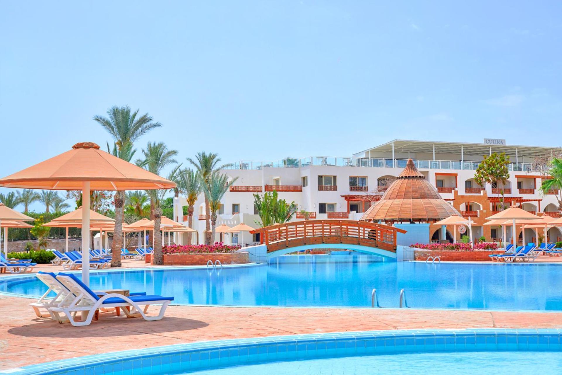Pickalbatros Royal Grand Sharm - Adults Friendly 16 Years Plus Екстериор снимка The photo depicts a beautiful resort setting featuring a large, inviting swimming pool. There are several lounge chairs positioned around the pool, along with straw umbrellas providing shade. In the background, there is a charming wooden bridge archi